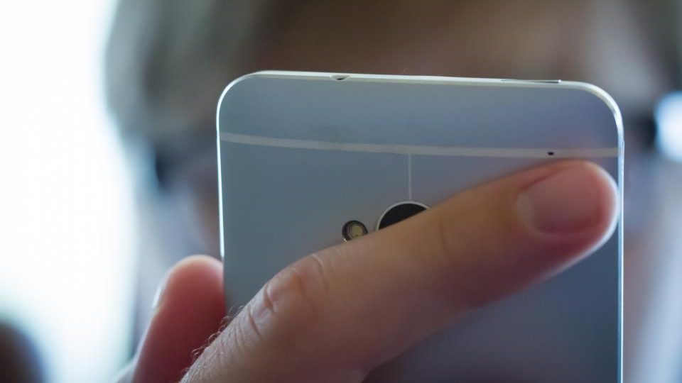 A hand holding a mobile phone, close up and softly lit