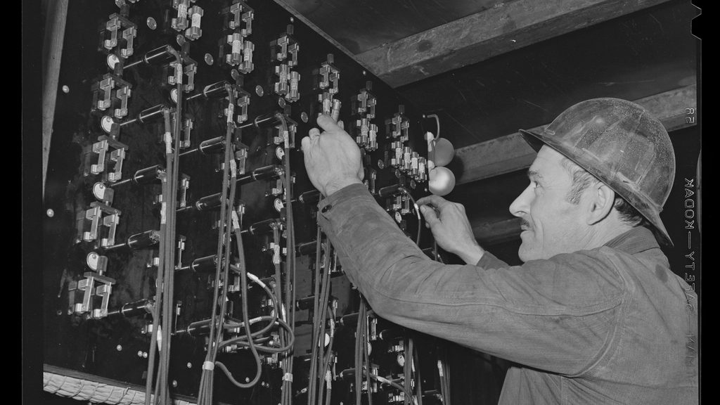 An operator working a manual telephone switchboard, black and white