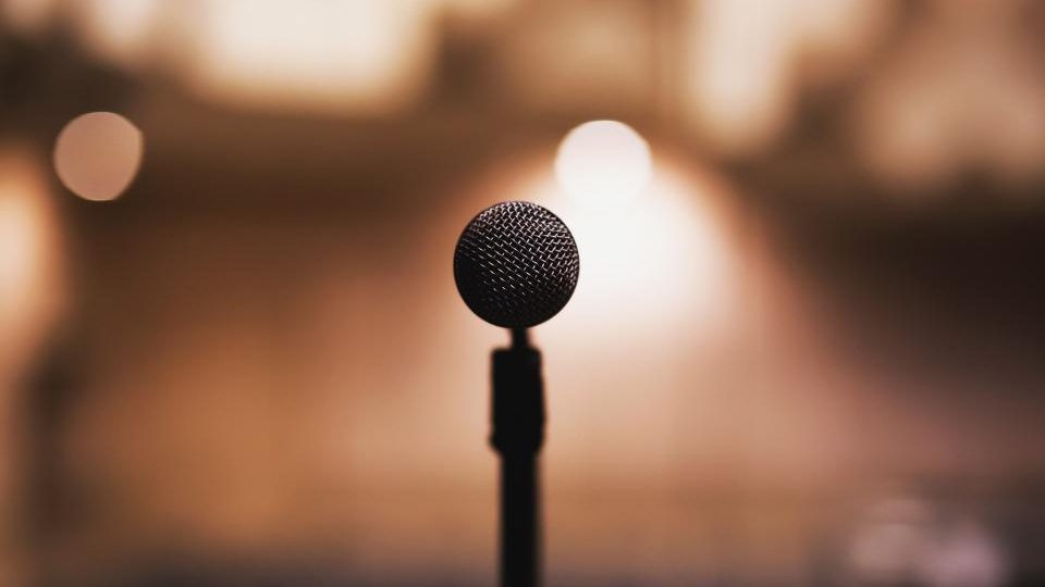 A microphone on a stand, shot against warm out of focus lights